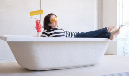 Creative story young happy woman sits in bathtub in the middle of the roomの写真素材