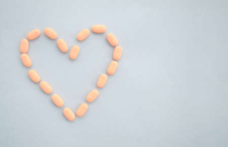 Medications tablets are laid out in the shape of a heart on a blue background. The concept of treatment of heart diseaseの写真素材