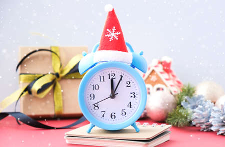 Alarm clock with red santa hat and pine cone on background, vertical christmas card idea