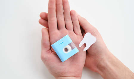 Dental floss in the hands of a guy on a blue background. A man's hand pulls dental floss. The...