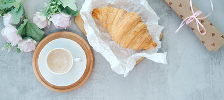 Cup of coffee with bouquet of pink tulips and croissant on white shabby chic background. Valentines, Mothers, Womens Day morning concept. Valentine's day breakfast. Top view. Copy space.の写真素材