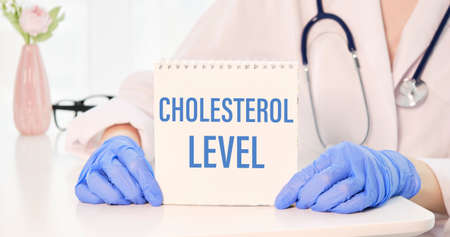 Text Cholesterol LEVELS on paper in doctor's hand with stethoscope, medical concept.の写真素材