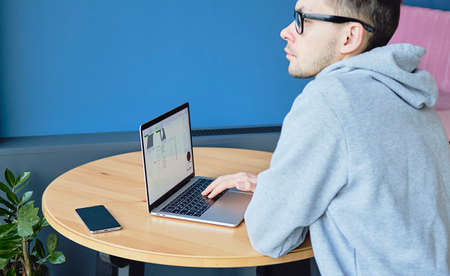 Young successful caucasian businessman works in an outdoor cafe using a computer. Business,...