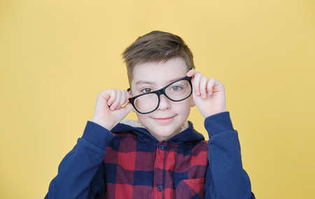 Boy in glasses and shirt isolated on yellow background, beautiful and handsome little boy.の写真素材