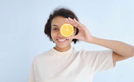 Photo of astonished dark skin girl hide eye half slice orange wear t-shirt isolated on turquoise...