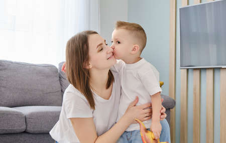 A little boy taking his mum in his arms in the bedroom, happy mother's day.の写真素材