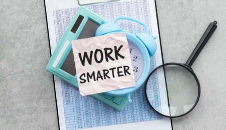 work smarter text on a pink card on the background of reports on the gray table.