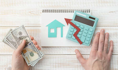 Real Estate Insurance And Protection. The man hands hold dollars with a calculator and a figurine of...