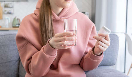 Close-up woman holding pills time to take medications, cure for headache, high blood pressure or...