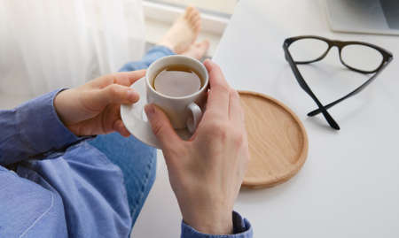 Female hands holding hot cup of coffee or tea.