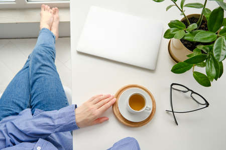 Asian business woman drinking coffee at home office enjoying the view of nature from window with...