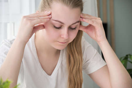 Young woman with headache in home interior.の写真素材
