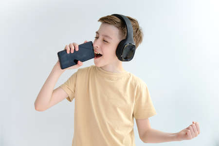 boy in headphones and with a phone in his hands sings into a telephone microphone.
