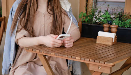 Beautiful young hipster woman hands holding mobile smart phone with hot coffee cup at cafe shop,cyber loveの写真素材
