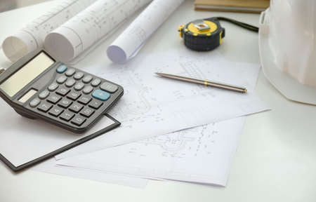 Construction drawings with tools on wooden table isolated on white background.