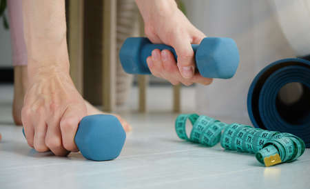 portable woman doing squats while holding dumbbells with straight hands.