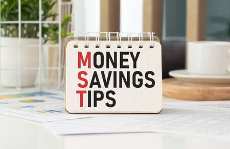 Money Savings Tips, text on small notepad with pen and calculations.の写真素材
