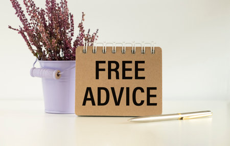 Free Advice text on a notebook standing near a flower on a light background and a pen lying Business concept.の写真素材