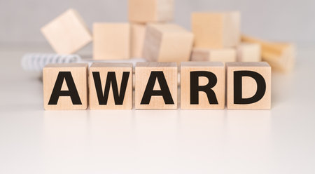 The text of the AWARD on wooden cubes on a light background, a table with a stack of books and wooden cubes.の写真素材