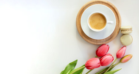 A bouquet of white tulips, cup of coffee with a love note and envelope on white boards.の写真素材