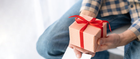 The concept of "HAPPY FATHER'S DAY" Box with a gift in a red ribbon with a bow in the hands of a man.の写真素材