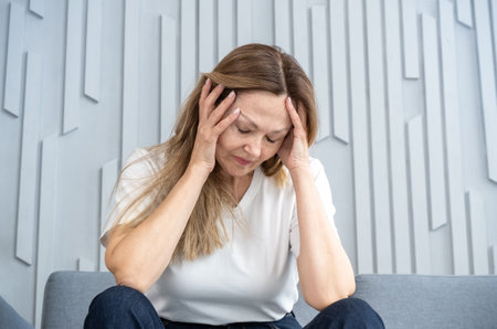 Woman suffering from stress grimacing in pain, Woman at work suffering painful headache.の写真素材