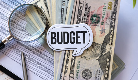 The text BUDGET on office desk with Banknotes, pen, magnifying glasses and financial charts.の写真素材