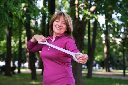 Portrait of a beautiful elderly woman doing exercises. Portrait of fit mature woman smiling on park background. Athletic senior womanの写真素材