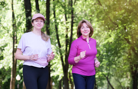 Elderly women girlfriends on a jog. They hug and smile. Healthy lifestyle, exercise, mental health and active sport photo conceptの写真素材