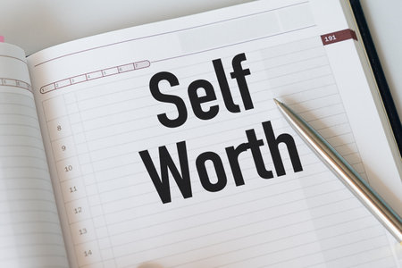 Paper notebook with handwritten text SELF WORTH, refers to self-love, being confidence with...