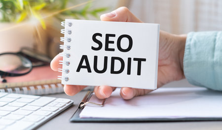 Seo Audit text on the blue paper in hands, keyboard, penの写真素材