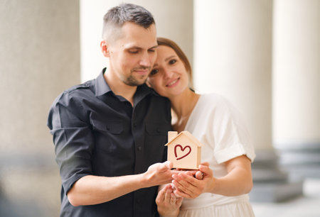 Cute young couple holding a small model house, home loan concept, renting or buying real estate.の写真素材