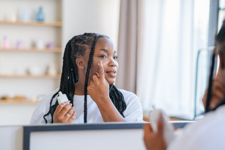 Cream, moisturizer and facial black woman in skincare, beauty or cosmetics promotion against a white wall. Face, calm and people generation or model lotion, sunscreen or skin care moisturizerの写真素材