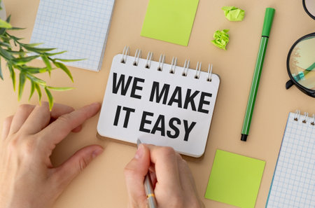 We make it easy text in the notebook on a yellow table. Top view - business concept.の写真素材