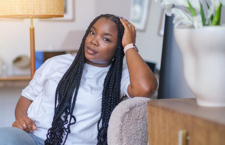 Portrait of a young dark-skinned woman sitting on an armchair at home, Concept of mental health and happinessの写真素材