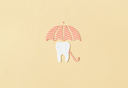 Tooth under an umbrella on a yellow background. Dentist concept. Dentistry and. Dental Health Concept.の写真素材