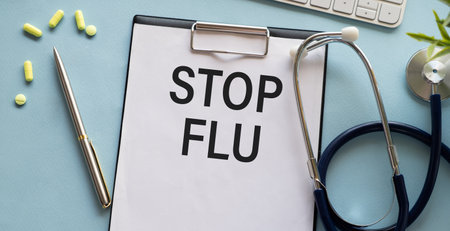 Paper with text STOP flu on blue table with stethoscope.