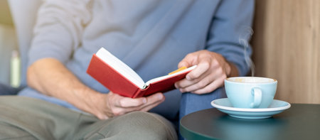 Man drinking morning tea in the kitchen reading paper book. Cozy home concept. Kitchen interior....