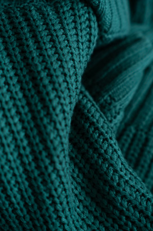 Knitted green background. Close-up of a knitted blanket. Wavy folds material. Knitted warm green...