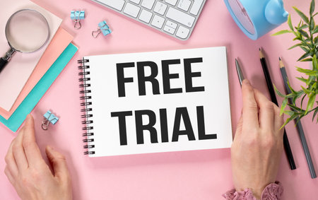 FREE TRIAL text on notebook and hands on pink background, business conceptの写真素材