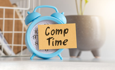 Text Comp Time on a Sticker glued to a blue alarm clock against the background of an officeの写真素材