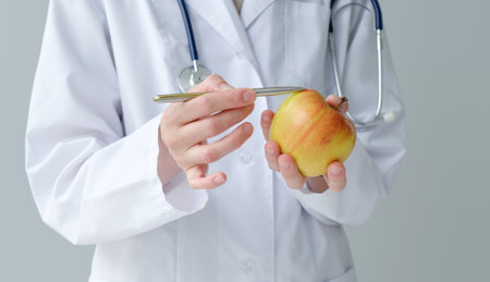 Doctor nutritionist in a white coat on a white background throws up apples in his handの写真素材
