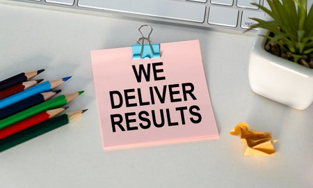 We deliver results. text on white paper, on a notepad, on a wooden background near pencils and a calculatorの写真素材
