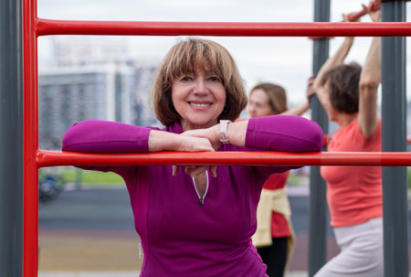 Athletic mature woman posing on an outdoor sports field. Senior woman portrait against the backdrop...