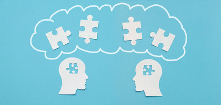 Paper figures of a human head with mosaic pieces on a blue background, social concept, cooperation,...