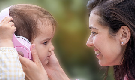 The mother put headphones on her daughter and listened to music happily.の写真素材
