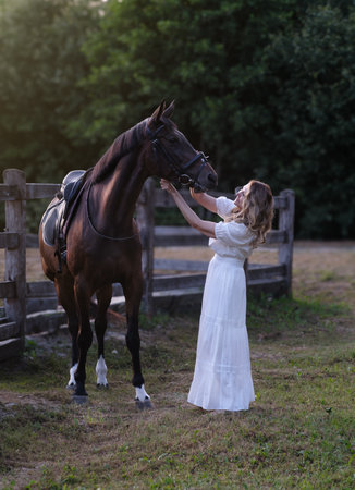 Adult Caucasian Blonde Female Horse Rider Looking At Her Horse While Holding The Reinsの写真素材