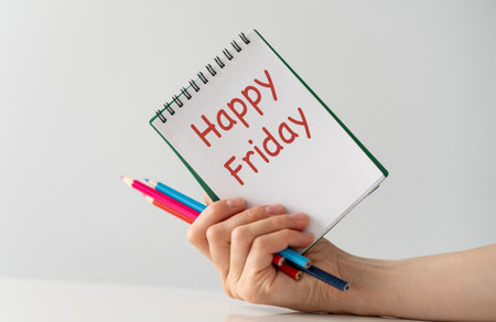 Happy Friday inscription on a notepad in hand on a light isolated backgroundの写真素材