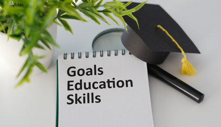 Text Goals Education Skills On Open Notebook with Magnifying Glass, Potted Flower on White Office...
