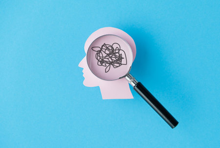 A magnifying glass is used to look at a head with a tangled mess of hair. Concept of confusion and...